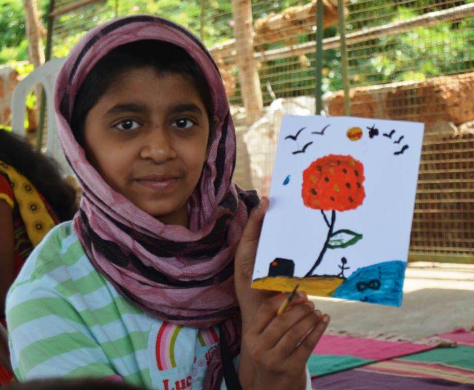 A sponsored child presenting her art at a summer camp